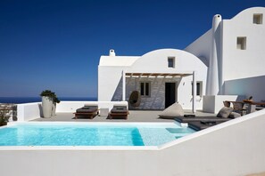 Un bâtiment moderne de couleur blanche, doté d’une piscine, d’un espace extérieur aménagé et offrant une vue sur la mer.