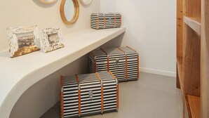 A modern interior with a curved white shelf displaying striped storage boxes and framed pictures. - Exclusive One Bedroom Villa - White Co (Santorini)