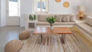 A modern living room with a sofa, a coffee table, and a plant. There are three round wall decorations and a lamp on a side table. - Exclusive One Bedroom Villa - White Co (Santorini)