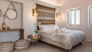 Un dormitorio con cama, mesita de noche, lámpara y almohadas decorativas.