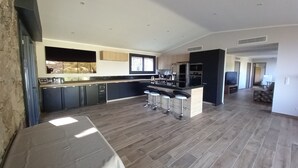 Une cuisine spacieuse dotée d’un îlot central, de tabourets de bar et d’un coin repas avec une table.