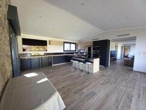 Une cuisine spacieuse dotée d’un îlot central, de tabourets de bar et d’un coin repas avec une table.