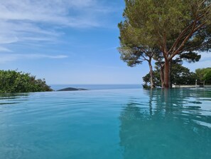 A clear infinity pool with a view of the ocean and a tree on the right side. - VILLA CASANOVA – FOR 2 TO 4 PEOPLE (Santa-Reparata-Di-Balagna)