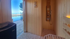 Un sauna en bois avec vue sur la mer, une horloge et un panneau de commande du sauna.