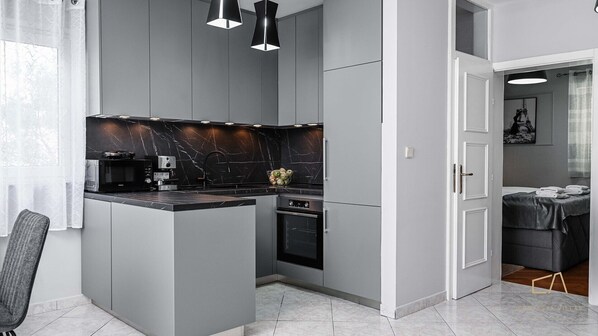 A modern kitchen with grey cabinets, a black marble backsplash, and a central island.