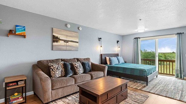 Une chambre à coucher moderne avec un grand lit, un canapé, une table basse en bois et un tableau au mur.