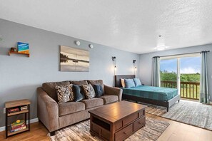 A modern bedroom with a large bed, a sofa, a wooden coffee table, and a painting on the wall. - AMAZING VIEW, Studio, Walk to Town (Room) (Long Beach)