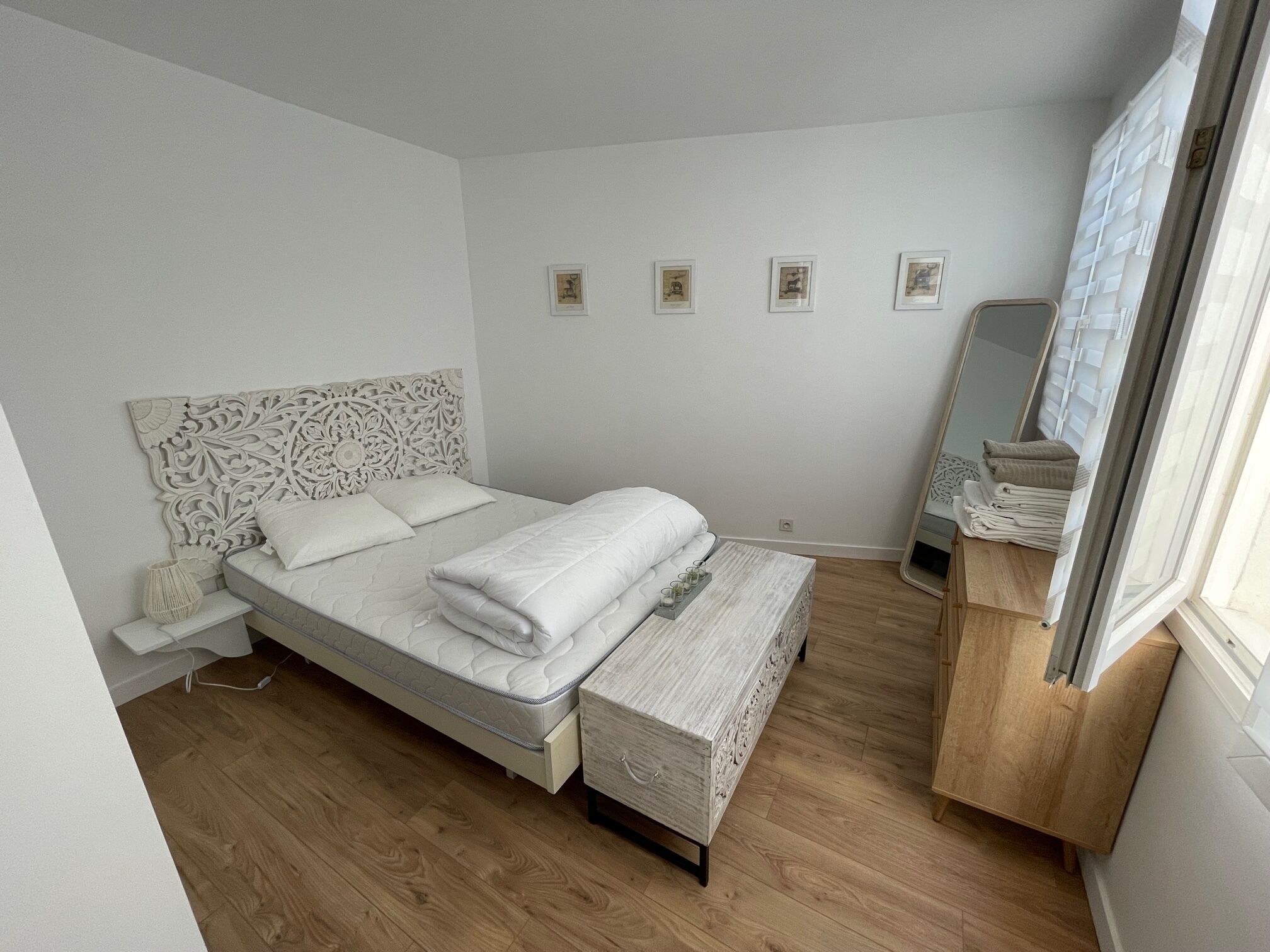 A bedroom with a bed, bedside table, and a mirror.