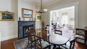 A dining room with a fireplace, a chandelier, and a view into the living area. - Liberty House, Historic Home | Centrally Located (Savannah)