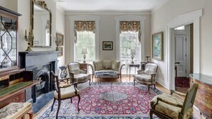 A formal room with a fireplace, multiple chairs, a coffee table, and a large mirror. - Liberty House, Historic Home | Centrally Located (Savannah)