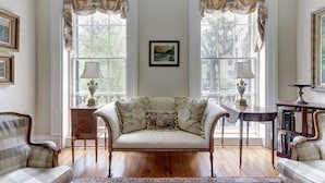 A room with a sofa, a side table, a lamp, and a bookshelf. - Liberty House, Historic Home | Centrally Located (Savannah)