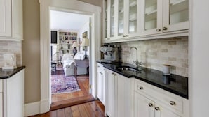 A kitchen with white cabinets, a black countertop, and a tiled backsplash. - Liberty House, Historic Home | Centrally Located (Savannah)