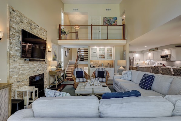 A spacious living area with a fireplace, a dining table, and a kitchen in the background.