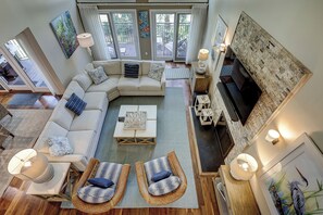 A spacious living room with a sectional sofa, two wicker chairs, a coffee table, and a fireplace.