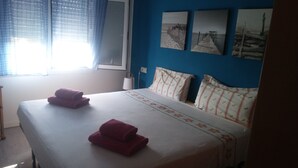 A hotel room with a bed, two pillows, a window with curtains, and three framed pictures on the wall. - Apartamento con Encanto al Lado de la Playa El Golfet (Calella de Palafrugell)