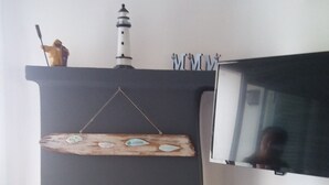 A fireplace with a black mantle, a wooden plaque, and a small lighthouse model above it. - Apartamento con Encanto al Lado de la Playa El Golfet (Calella de Palafrugell)