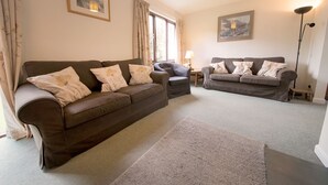 A living room with two sofas, a chair, a lamp, and a rug. - Beck Yeat Cottage - Coniston - close to lake (Coniston)