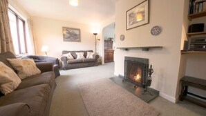 A living room with a fireplace, two sofas, a rug, and a bookshelf. - Beck Yeat Cottage - Coniston - close to lake (Coniston)