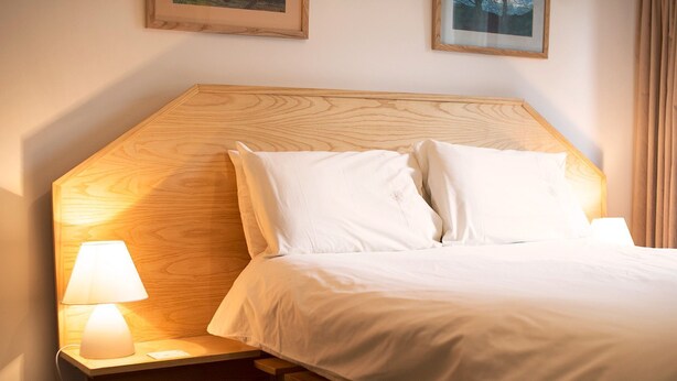 A neatly made bed with white linens and pillows, a wooden headboard, and a bedside lamp on a wooden nightstand. - Beck Yeat Cottage - Coniston - close to lake (Coniston)