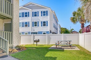 A residential building with a white exterior, a fenced backyard, a picnic table, and a mailbox. - Myrtle Beach Condo: Balconies, Walk to Beach! (Myrtle Beach)
