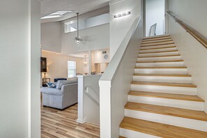 Una escalera de madera con barandillas blancas que sube a un segundo piso.