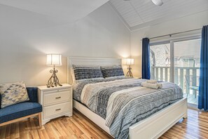 Un dormitorio con cama, mesitas de noche, una silla y un balcón con barandilla.
