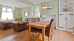 Ein gemütliches Wohnzimmer mit Esstisch aus Holz, Ledersesseln und einem braunen Ledersofa.