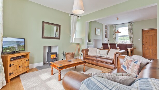 Ein gemütliches Wohnzimmer mit Kamin, Fernseher, Sofa und Essbereich.