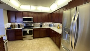Une cuisine moderne avec des meubles en bois foncé, des appareils électroménagers en acier inoxydable et un dosseret carrelé.