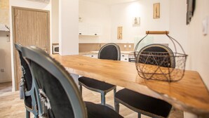 Un espace repas moderne avec une table en bois, des chaises à revêtement noir et un panier en métal.