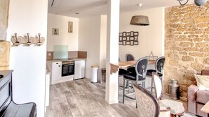 Une cuisine moderne avec des armoires blanches, un four encastré et un coin repas comprenant une table en bois et des chaises à revêtement noir.