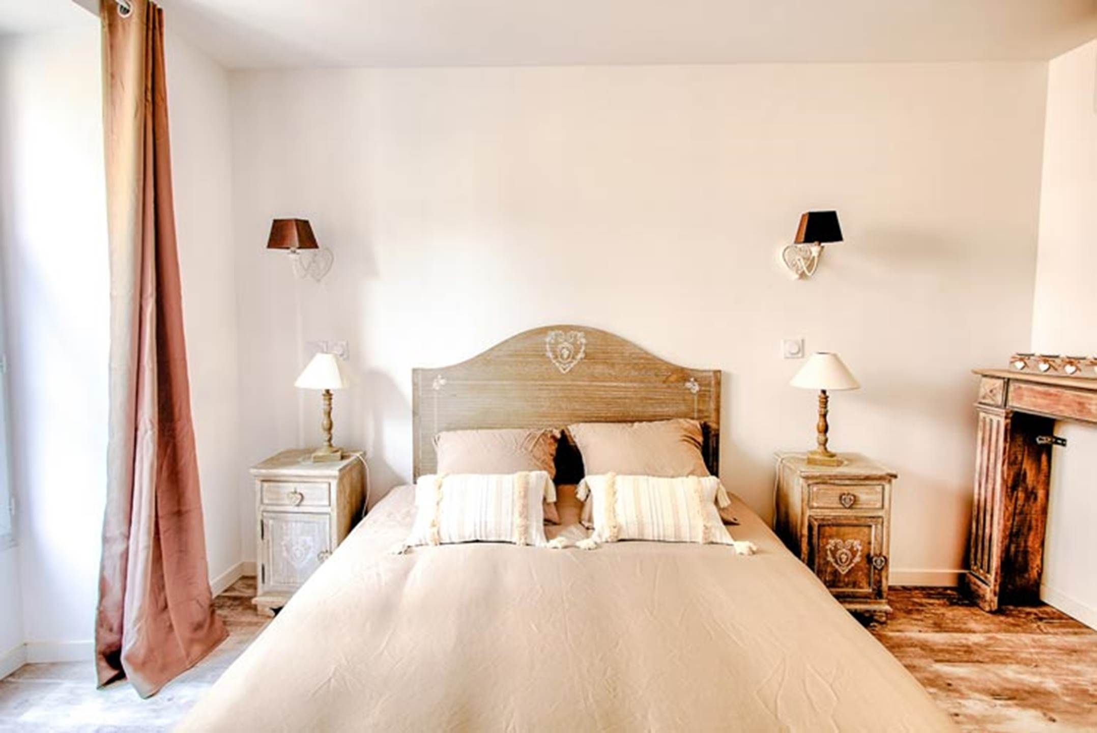 Une chambre à coucher avec un grand lit, deux tables de chevet avec des lampes, une commode et un miroir.
