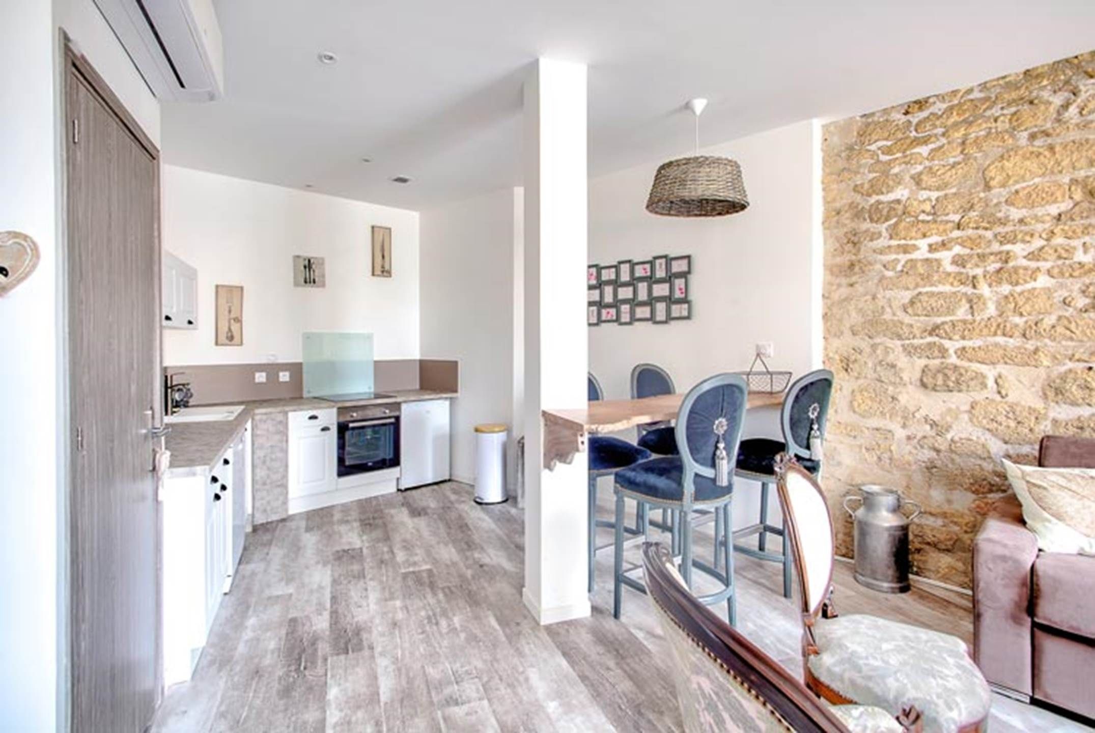 A modern kitchen with a dining area, stone wall, and a cozy seating area.