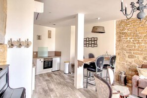 A modern kitchen with white cabinets, a dining area with a stone wall, and a chandelier. - ⚘ Superb luxury T2 ⚘ for 4 people (Montignac)