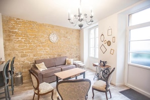 A cozy living room with a stone wall, a sofa, a coffee table, and a chandelier.