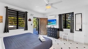 Une chambre moderne avec un lit, un téléviseur et un ventilateur de plafond.