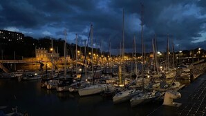 A marina at dusk with numerous boats docked, a bridge in the background, and buildings on the shore. - "La Chaumière de Nanou", with large garden and close to the sea. (Saint-Valery-en-Caux)