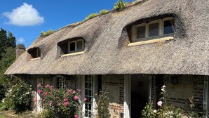 A traditional thatched-roof cottage with a garden entrance, a small window, and a brick wall. - "La Chaumière de Nanou", with large garden and close to the sea. (Saint-Valery-en-Caux)