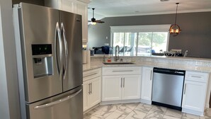 A modern kitchen with stainless steel appliances, marble flooring, and white cabinetry. - Pool, Hot Tub & Golf Views... What More Could You Need?! (The Villages)