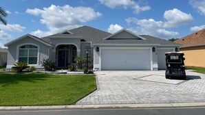 A residential house with a garage, driveway, and a golf cart parked in front. - Pool, Hot Tub & Golf Views... What More Could You Need?! (The Villages)