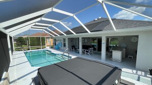 A covered swimming pool area with a lounge chair, a small table, and a clock on the wall. - Pool, Hot Tub & Golf Views... What More Could You Need?! (The Villages)