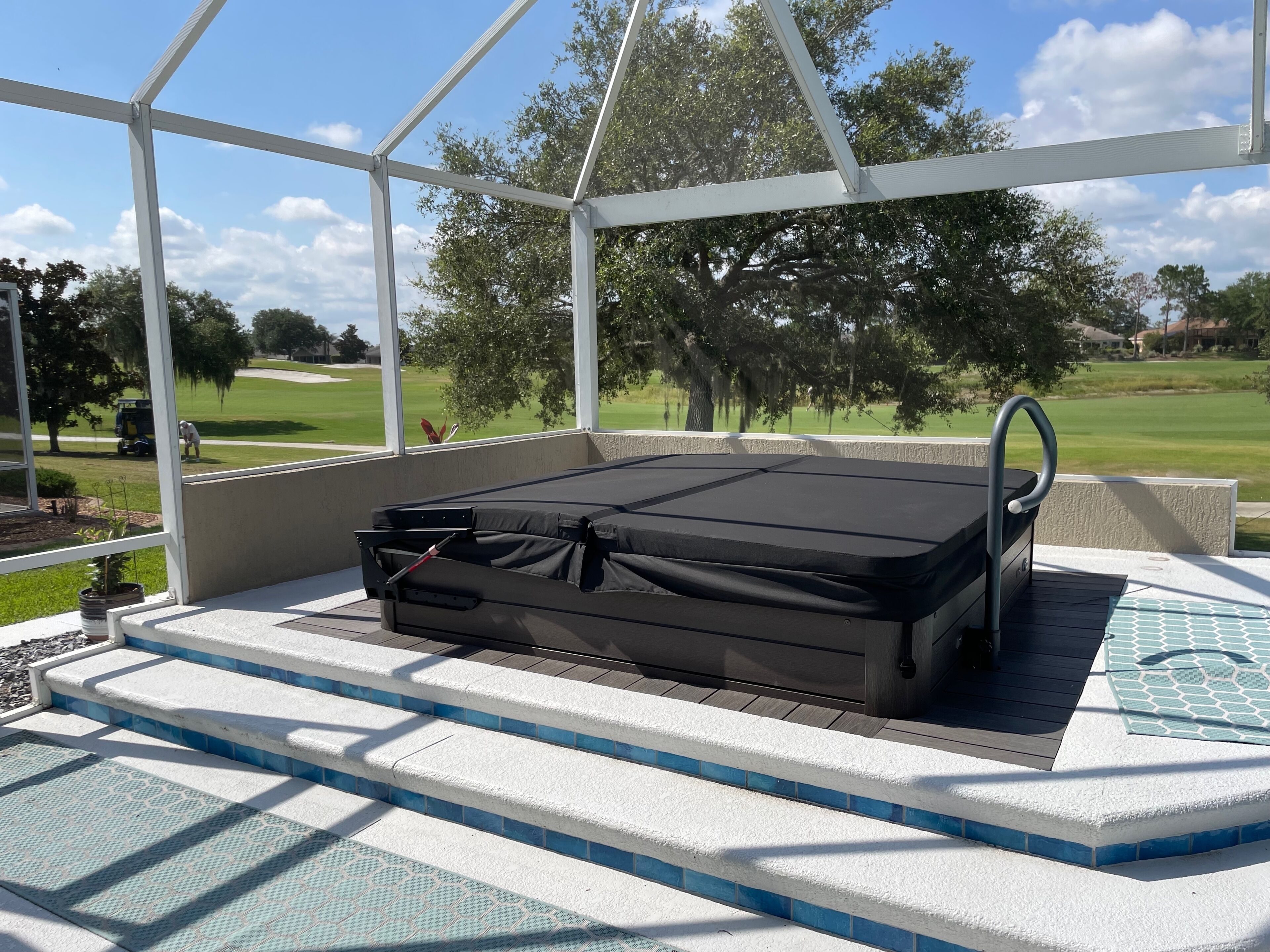 A covered outdoor seating area with a mattress, steps, and a view of a golf course.