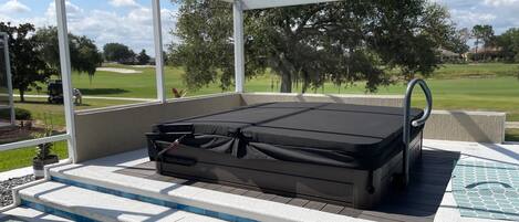A covered outdoor seating area with a mattress, steps, and a view of a golf course.