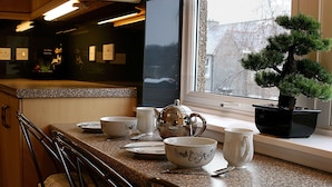 A kitchen counter with various dishes, a teapot, and a potted plant by a window. - Linden Apartment -  an apartment that sleeps 4 guests  in 2 bedrooms (Stirling)