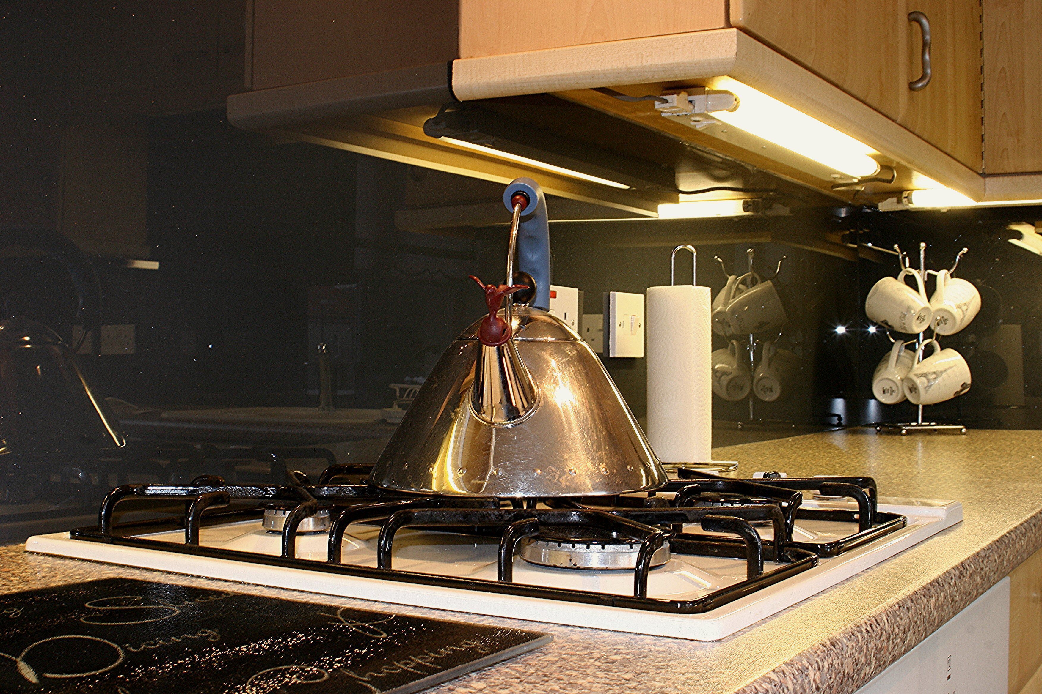 Une cuisine équipée d’une cuisinière à gaz, d’une bouilloire et d’un plan de travail muni d’un porte-essuie-tout.