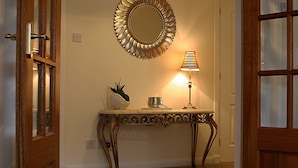 A hallway with a decorative mirror, a table with a lamp, and a potted plant. - Linden Apartment -  an apartment that sleeps 4 guests  in 2 bedrooms (Stirling)