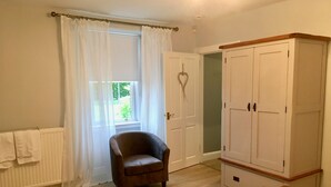 Um quarto com cama de madeira, guarda-roupa, cadeira e janela com cortinas.
