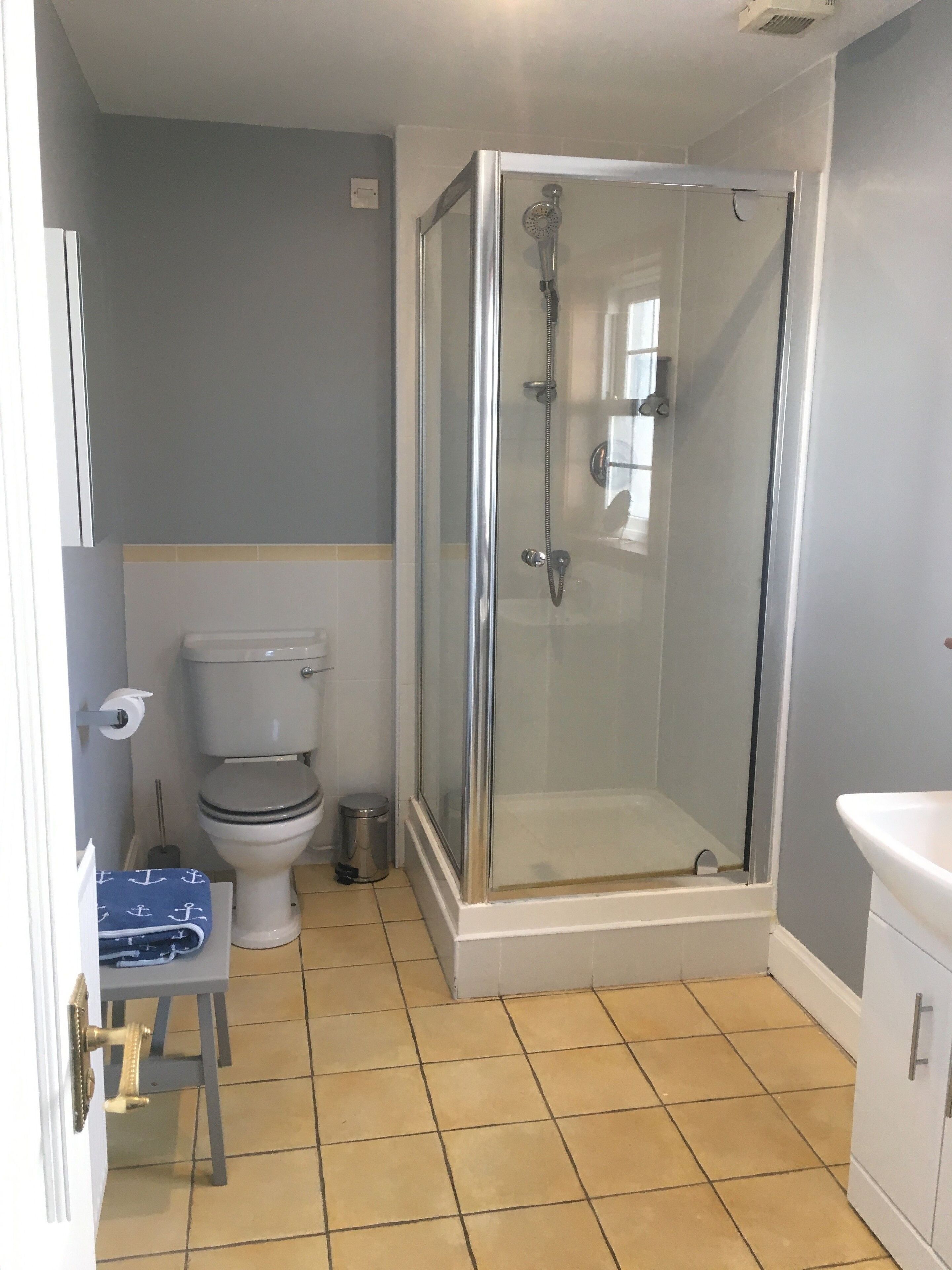 A bathroom with a glass-enclosed shower, a toilet, and a sink.