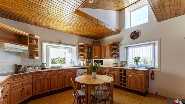 Una cocina con armarios de madera, una mesa de comedor con sillas y una ventana con persianas.