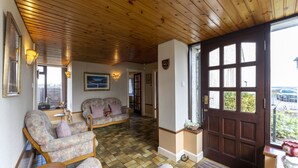 Un salón acogedor con techo de madera, sofás estampados y un ventanal con vistas.